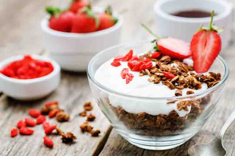fresh breakfast of granola, yogurt, nuts, goji berries and strawberries. tinting. selective focus
