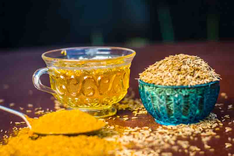 Cumin,Cuminum cyminum with its powder and its tea on brown wooden surface.