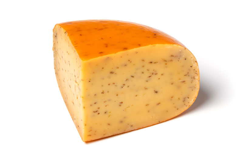 Piece of traditional mature Dutch cumin cheese isolated on white background