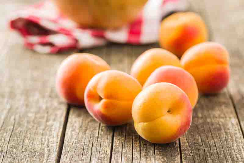 Sweet apricot fruits on old wooden table.