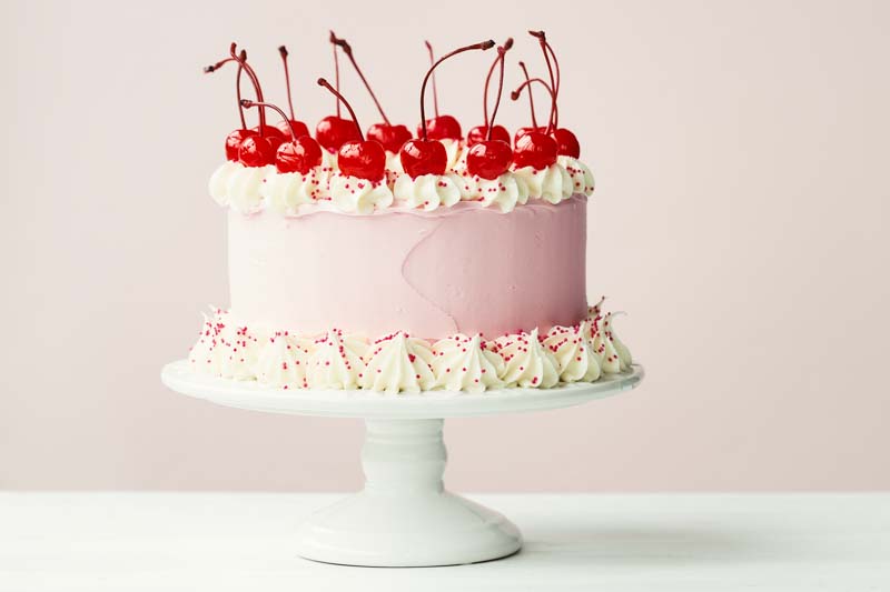 Cake decorated with frosting and maraschino cherries