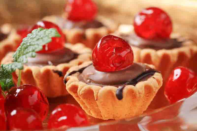 Chocolate filled tartlets topped with maraschino cherries