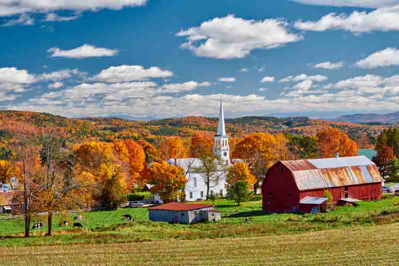 Congregational Church and farm with red barn at sunny autumn day in Peacham, Vermont, USA