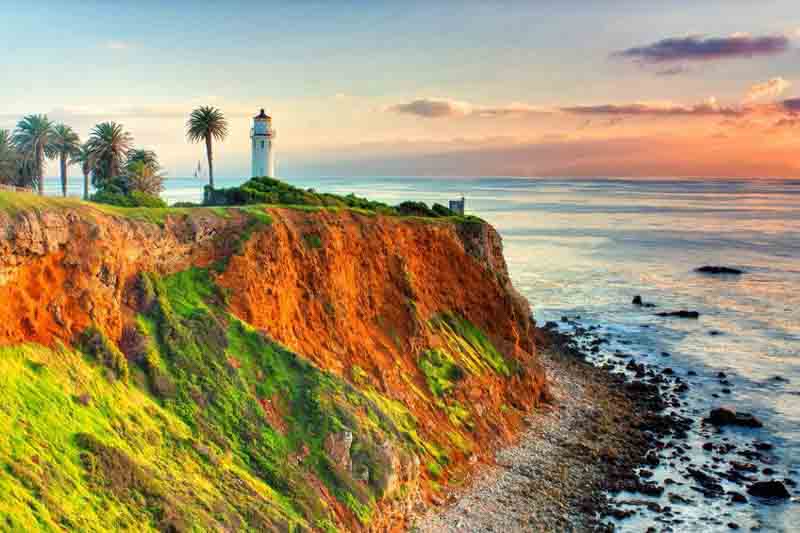 point vicente lighthouse as the sun sets over catalina island.