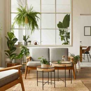 Modern scandinavian interior of living room with design grey sofa, armchair, a lot of plants, coffee table, carpet and personal accessories in cozy home decor